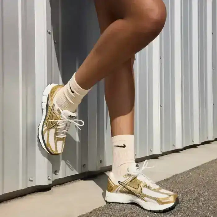Gold-colored and cream sneakers with layered panels and chunky soles.