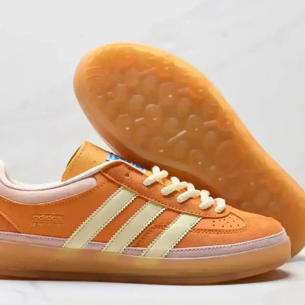 Orange and cream three-stripe low-top sneakers with gum soles.