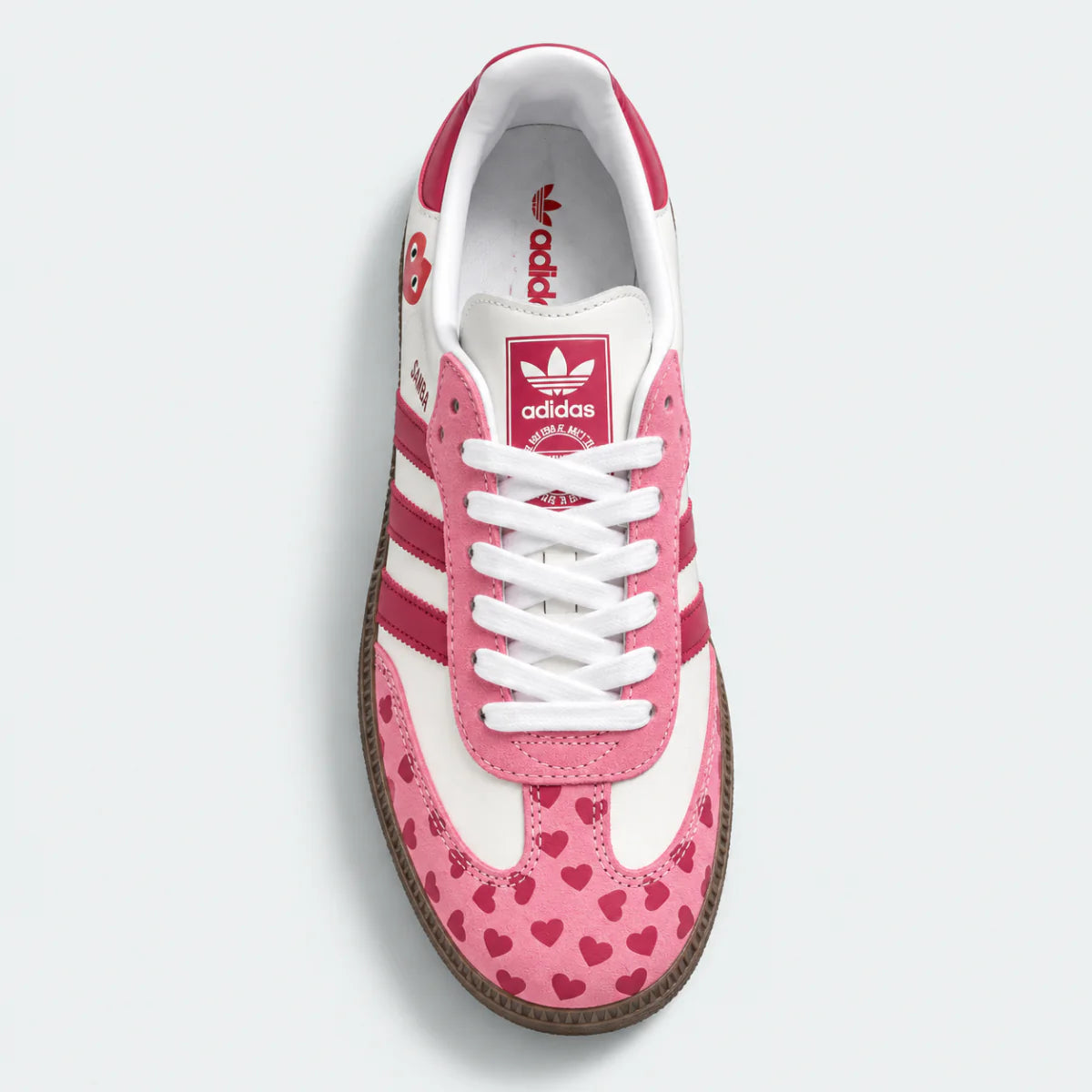 Pink heart-pattern sneaker with white laces, top view.