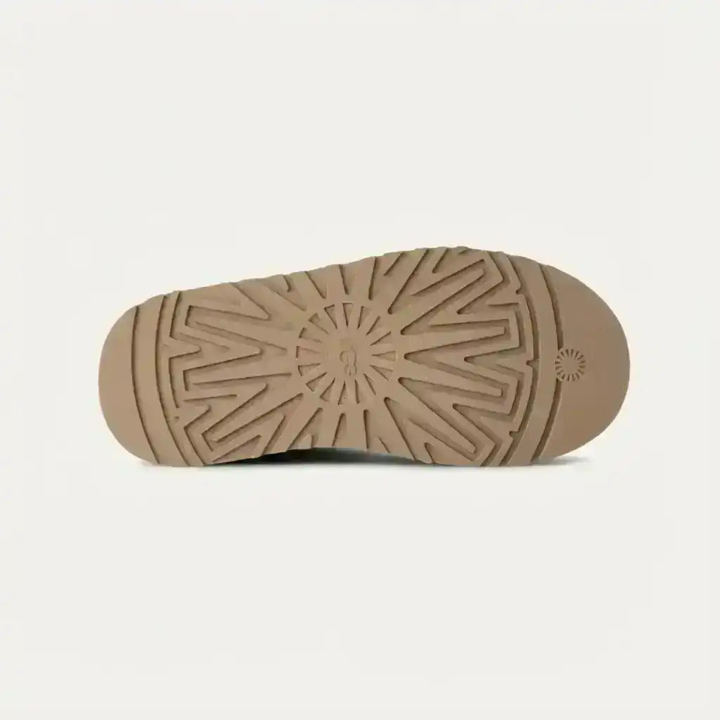 Beige slipper outsole with a radiating tread pattern, bottom view.