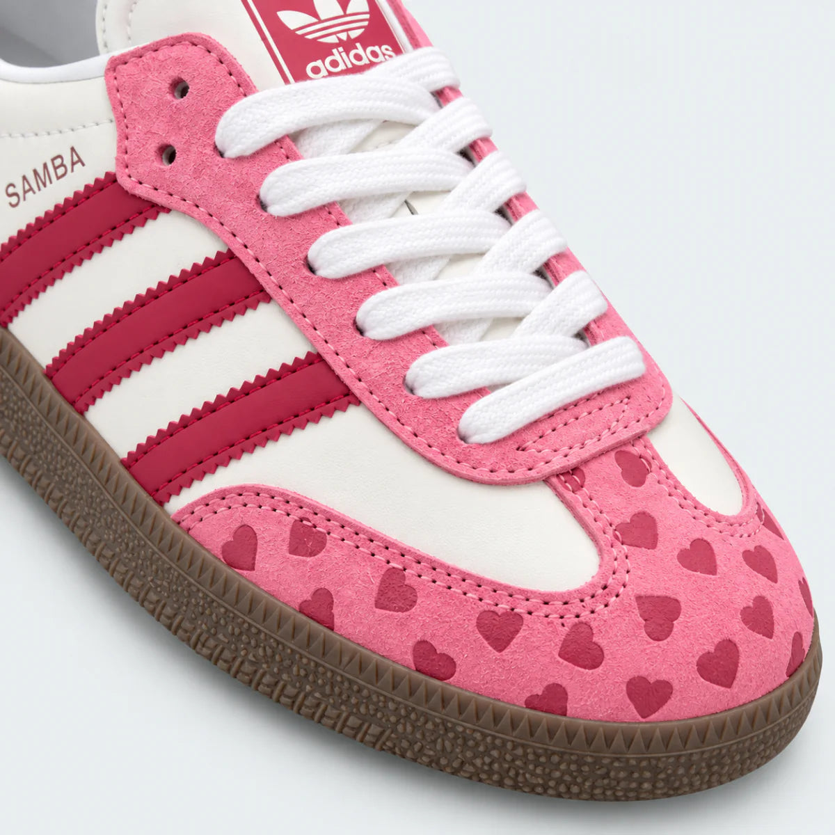 Pink and white heart-pattern low-top sneakers with gum soles.
