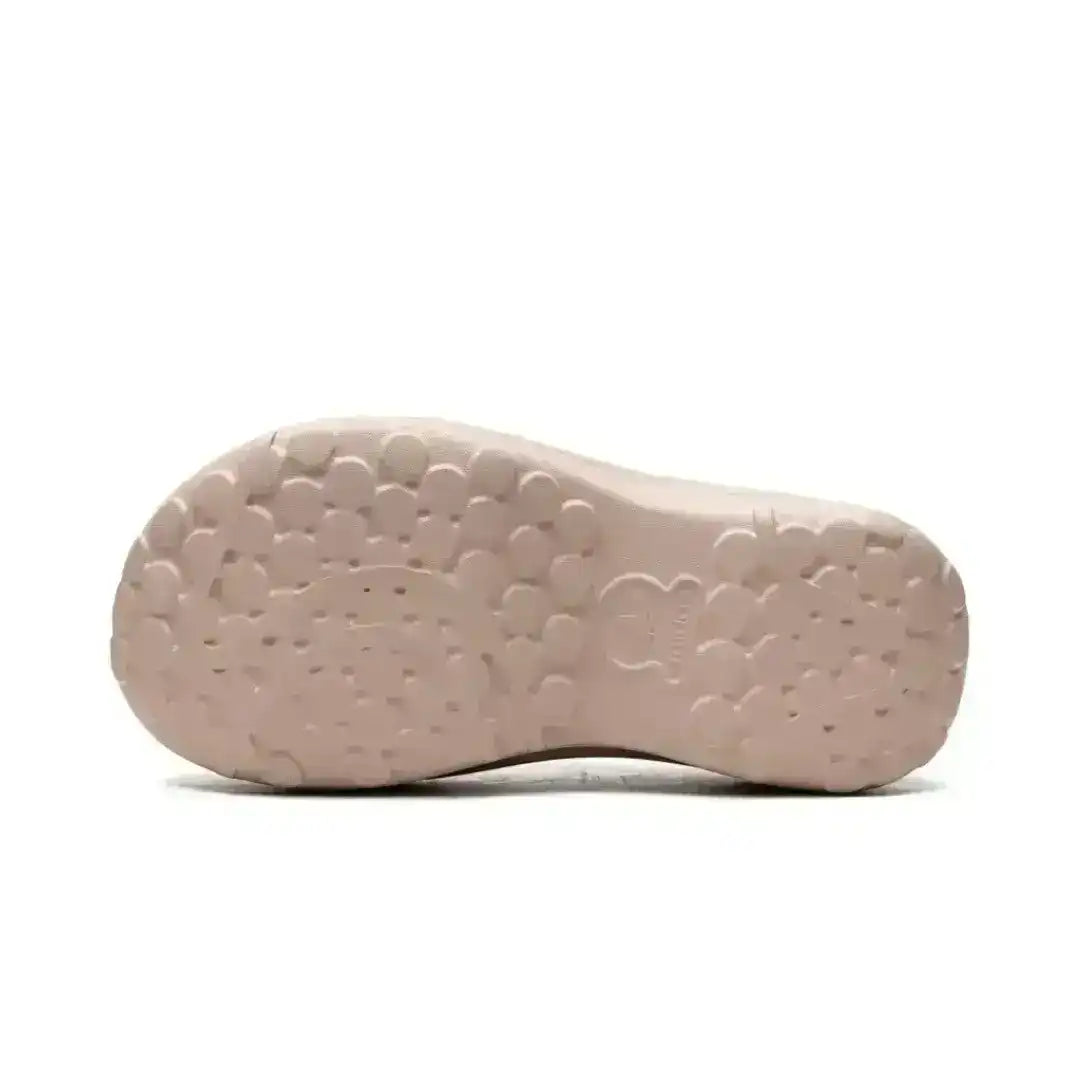 Cream molded clog outsole with rounded tread shapes, bottom view.