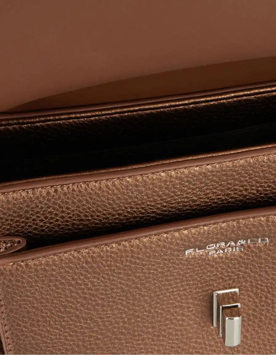 Close-up of a brown handbag's textured surface, zipper and hardware.