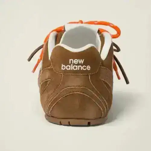 Brown low-top sneakers with orange laces and textured panels.