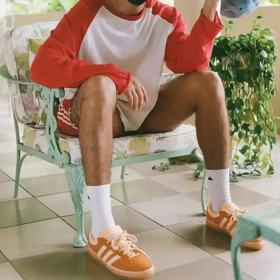 Orange and cream three-stripe low-top sneakers with gum soles.