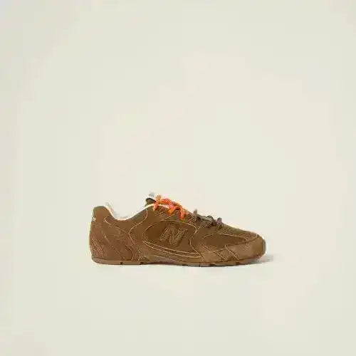 Brown low-top sneakers with orange laces and textured panels.