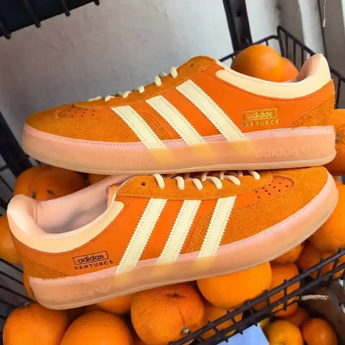 Orange and cream three-stripe low-top sneakers with gum soles.