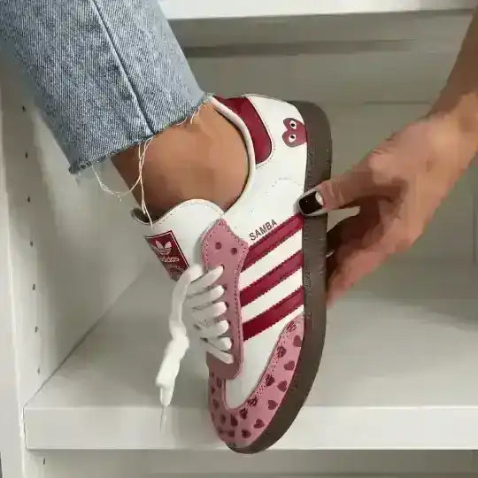 Pink and white low-top sneakers with small heart patterns.
