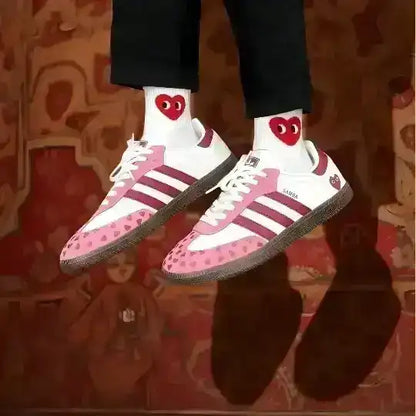 Pink and white low-top sneakers with small heart patterns.