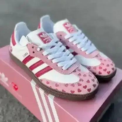 Pink and white Adidas sneakers with heart pattern on a pink box.