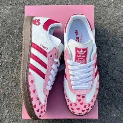 Pink and white low-top sneakers with small heart patterns.