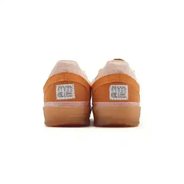 Orange and cream three-stripe low-top sneakers with gum soles.