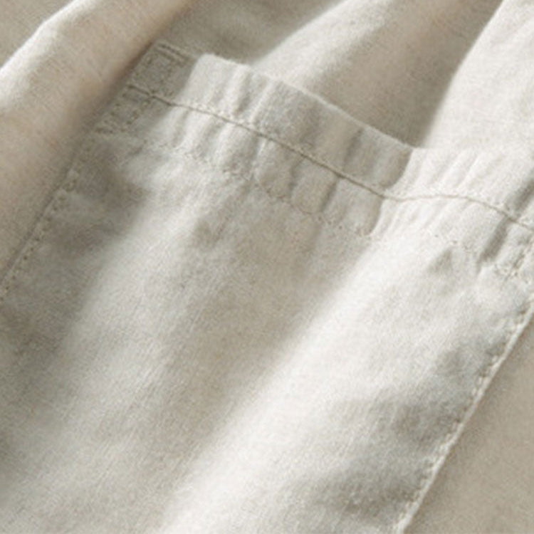 Close-up of a cream shirt's stitched chest pocket and fabric texture.