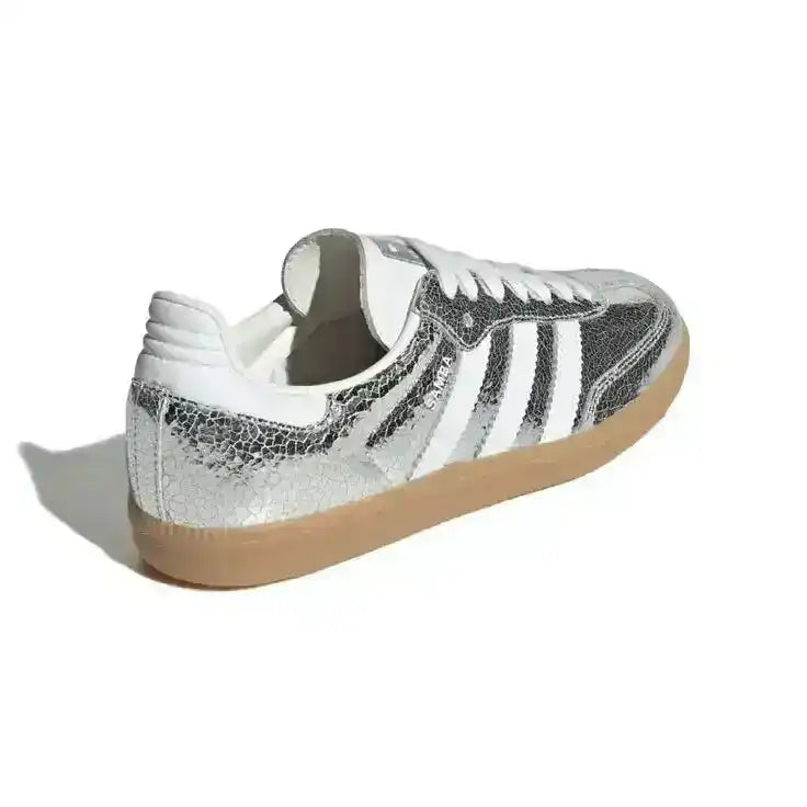 Silver-colored three-stripe low-top sneakers with gum soles.