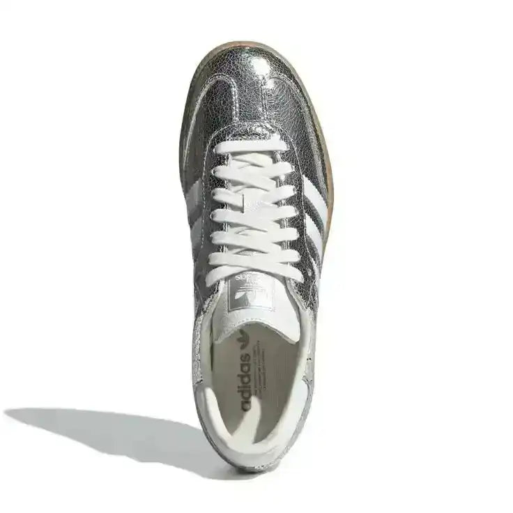 Silver-colored three-stripe low-top sneakers with gum soles.