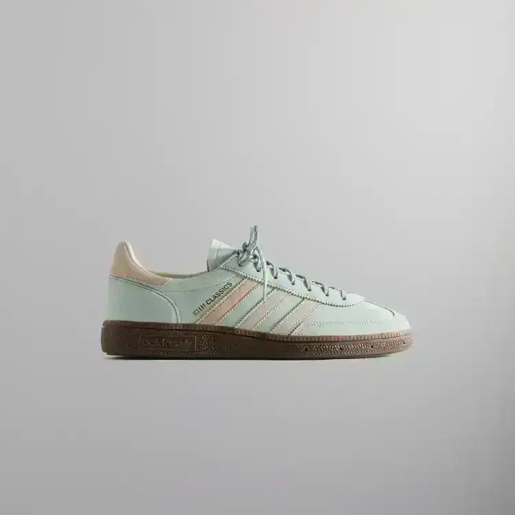 Pale mint low-top sneakers with cream stripes and brown soles.