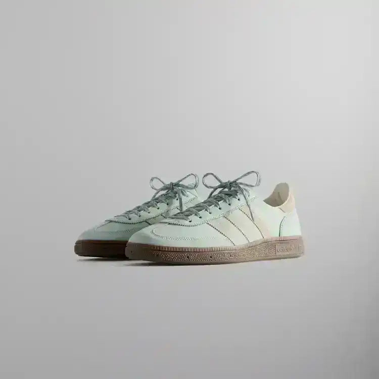 Pale mint low-top sneakers with cream stripes and brown soles.