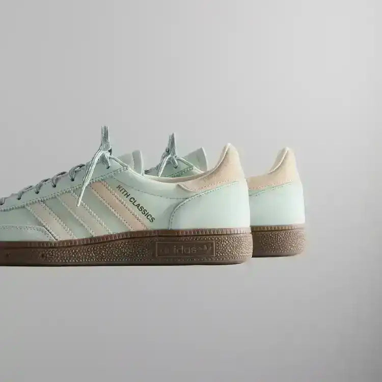 Pale mint low-top sneakers with cream stripes and brown soles.