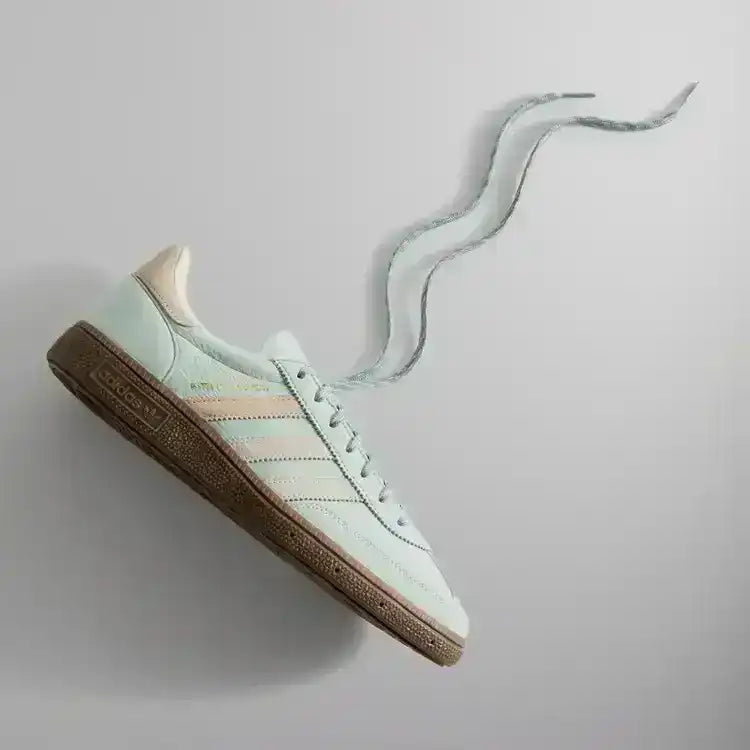 Pale mint low-top sneakers with cream stripes and brown soles.