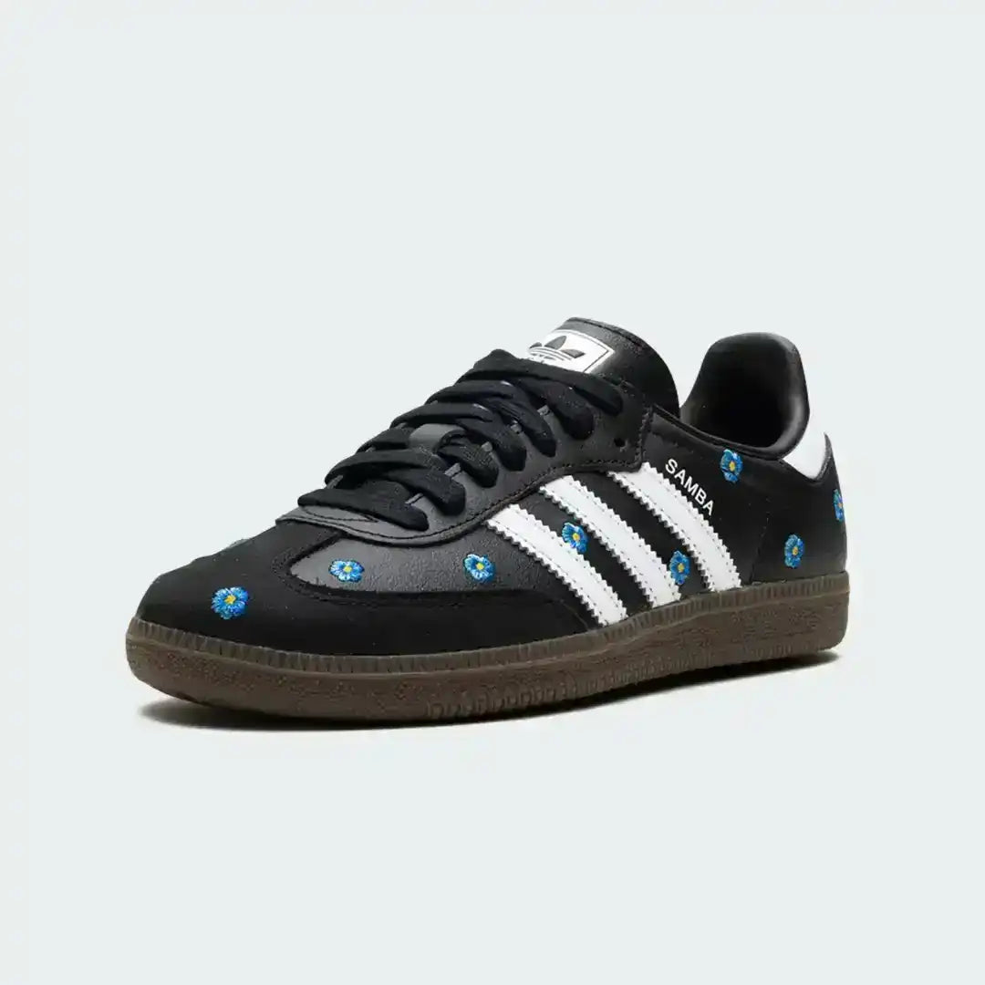 Black Adidas Samba sneakers showcasing embroidered blue flowers, premium leather texture, white stripes and a supportive gum outsole finish.