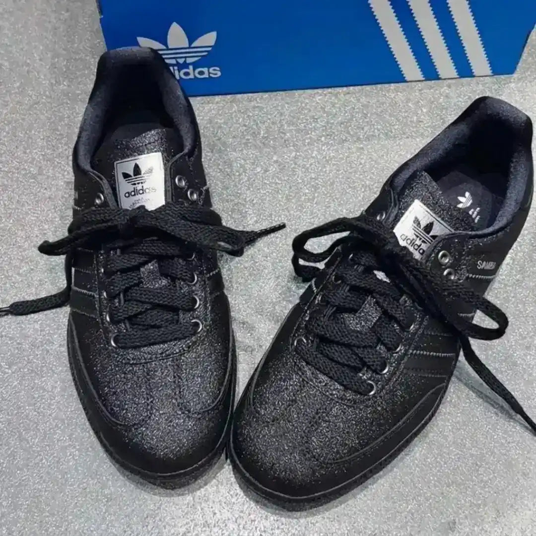 Adidas Samba black leather sneakers featuring a subtle glitter texture, black laces, silver tongue label and a dark gum sole for a bold lifestyle look.