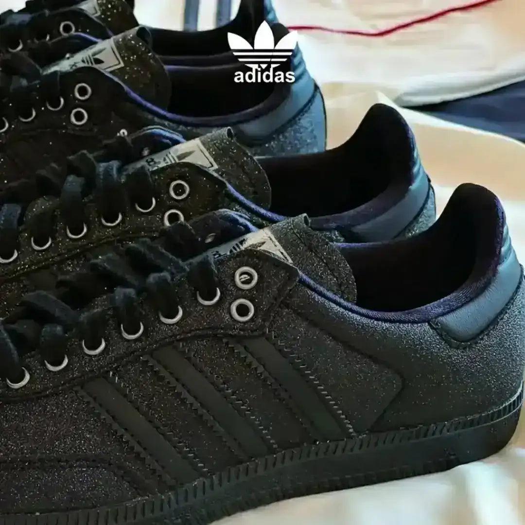 Black Adidas Samba shoes showcasing glitter-textured leather, classic branding elements, black laces and a sturdy dark gum sole for urban wear.