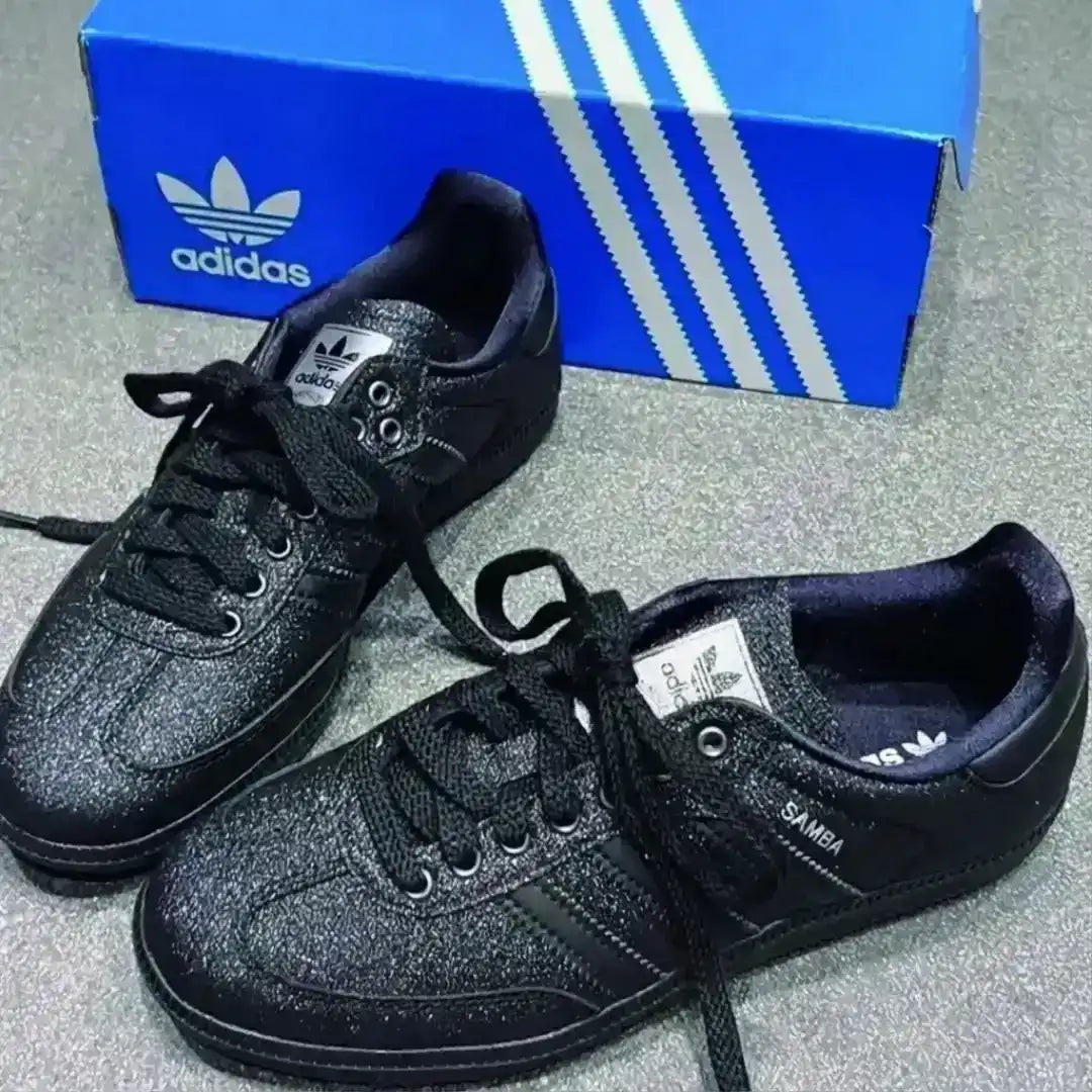 Black Adidas Samba shoes featuring a glittery upper, tonal black laces, metallic Adidas branding and a dark gum outsole for a clean stylish look.