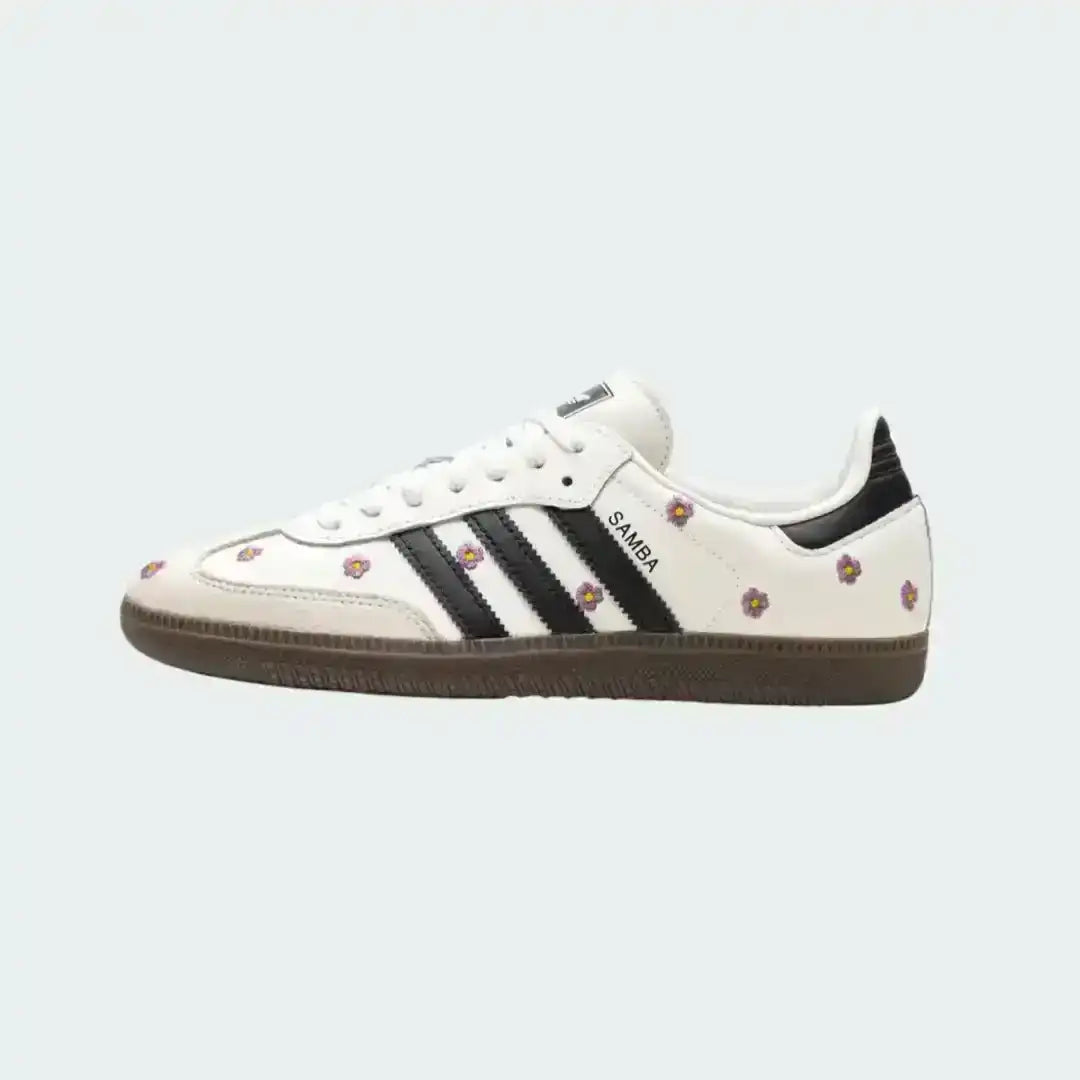 Adidas Samba floral edition in white leather with small pink embroidered flowers, bold black stripes and a dark gum sole for a vintage look.