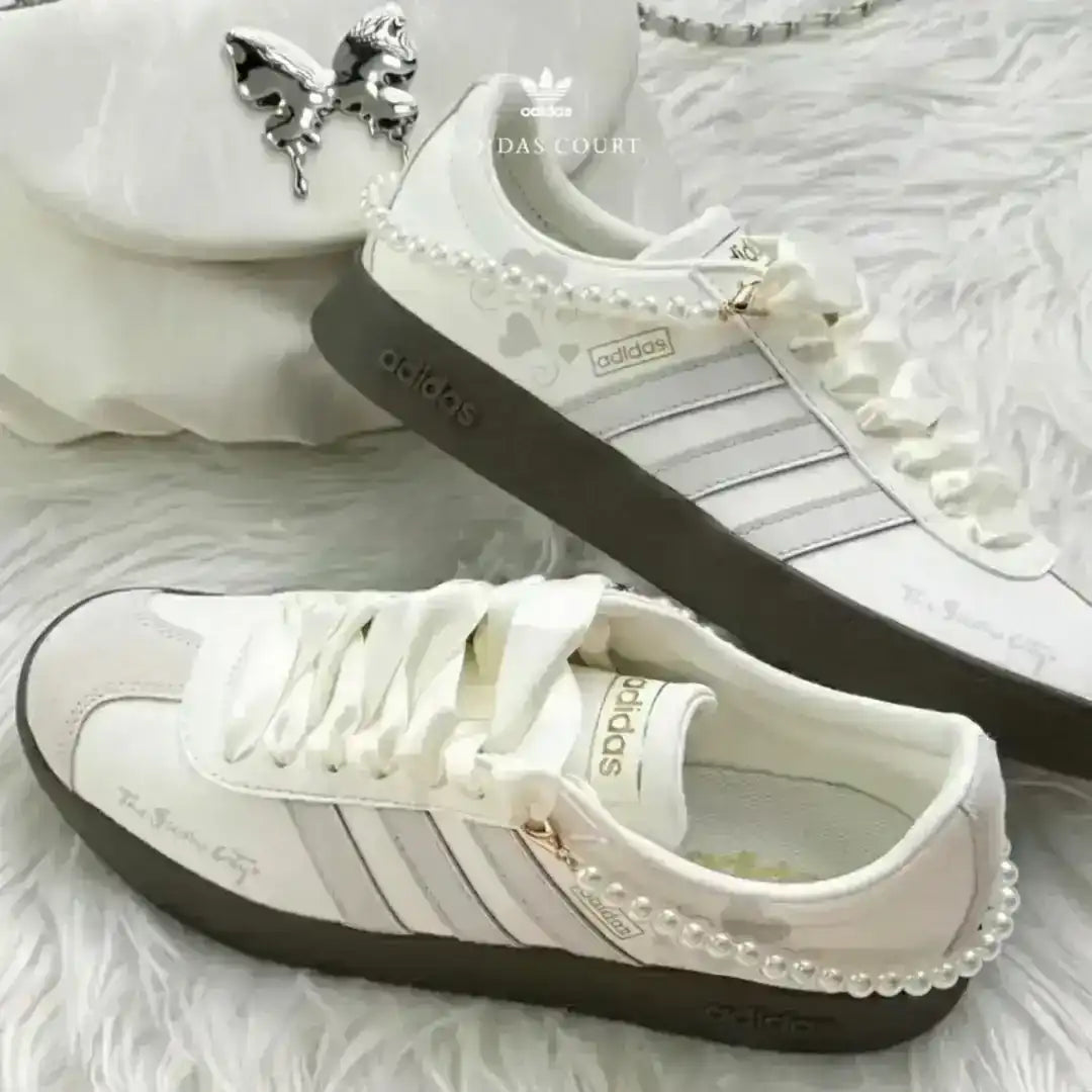 White Adidas lifestyle shoes featuring grey stripes and a pearl ankle accessory, completed with a textured dark gum outsole for comfort.