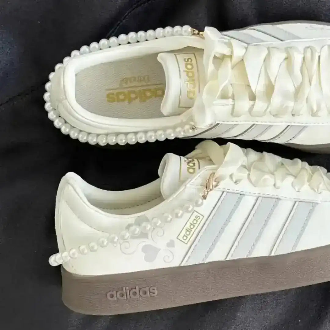 Stylish Adidas sneakers in white and grey with a pearl ankle strap, finished with a dark gum sole offering durability and aesthetic appeal.