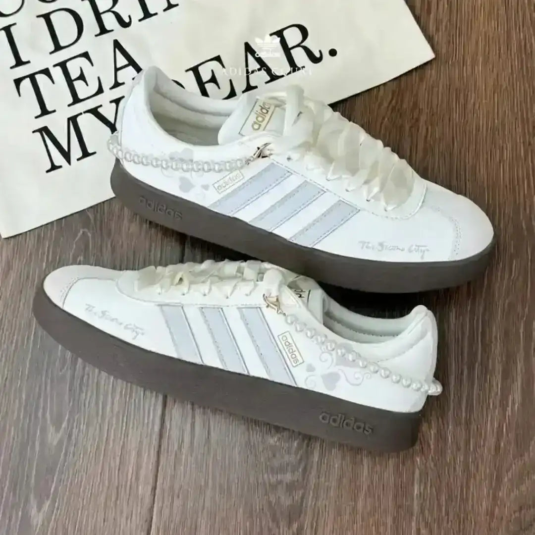 Adidas lifestyle edition sneakers in white and grey with a pearl ankle accessory and a dark gum sole for a stylish and feminine appearance.