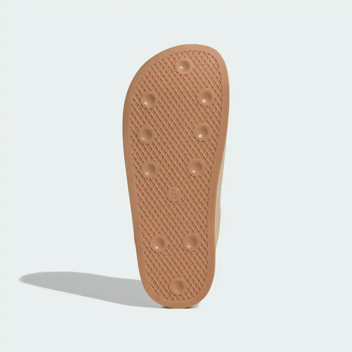 Tan slide-shoe outsole with small raised dots, bottom view.