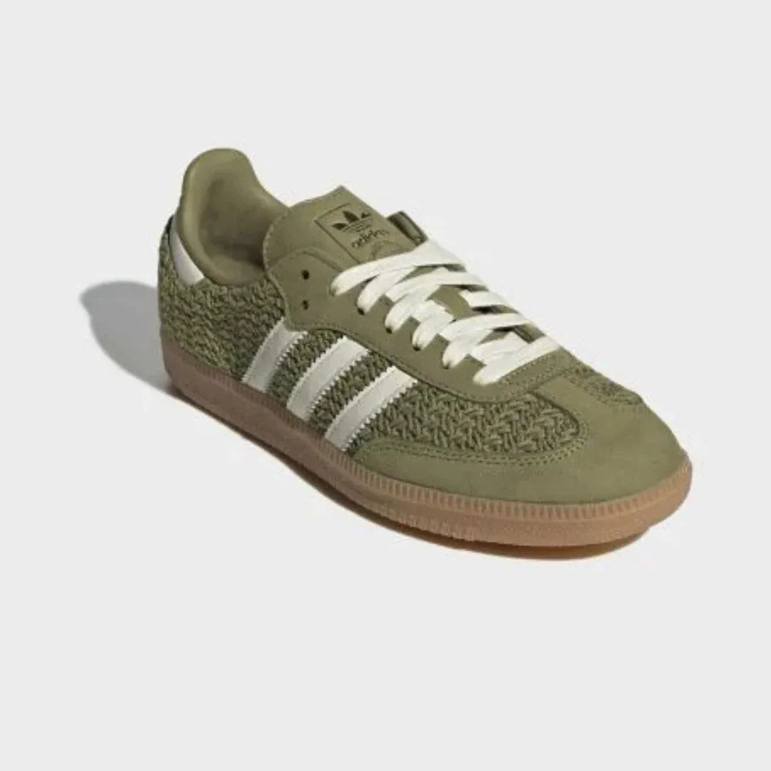 Olive green woven-texture low-top sneakers with cream stripes and gum soles.