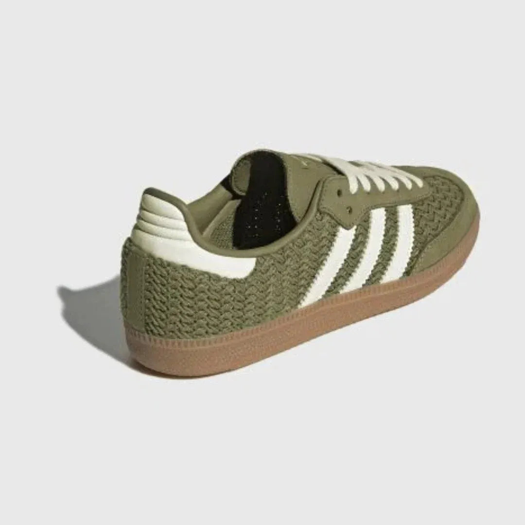 Olive green woven-texture low-top sneakers with cream stripes and gum soles.