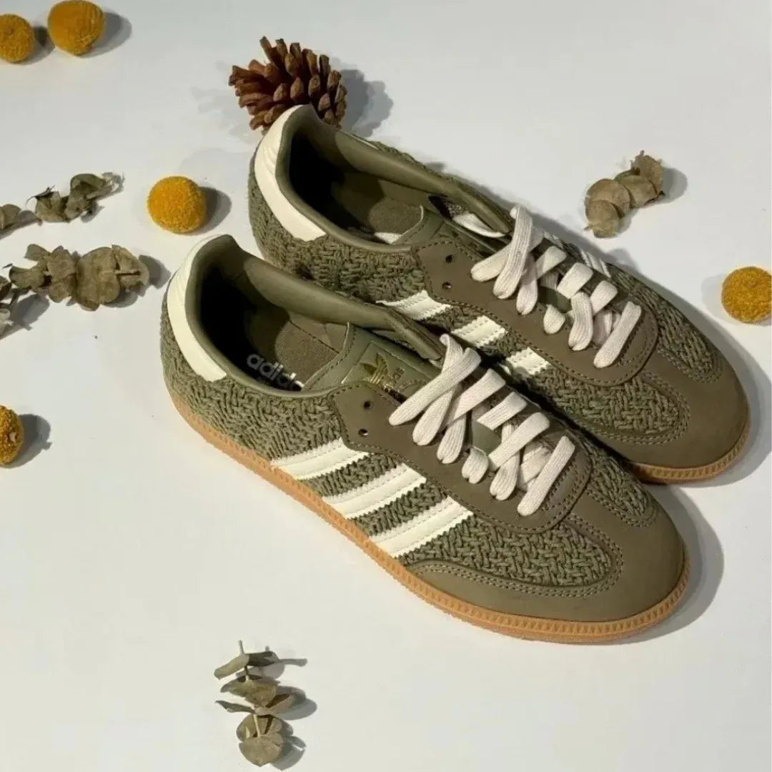 Olive green woven-texture low-top sneakers with cream stripes and gum soles.