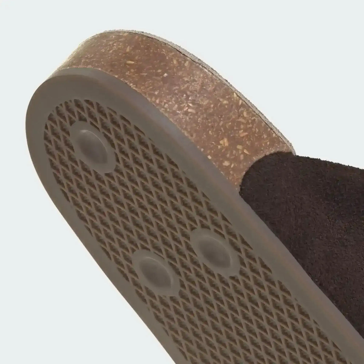 Brown slide-shoe outsole with honeycomb-like heel tread, close-up.