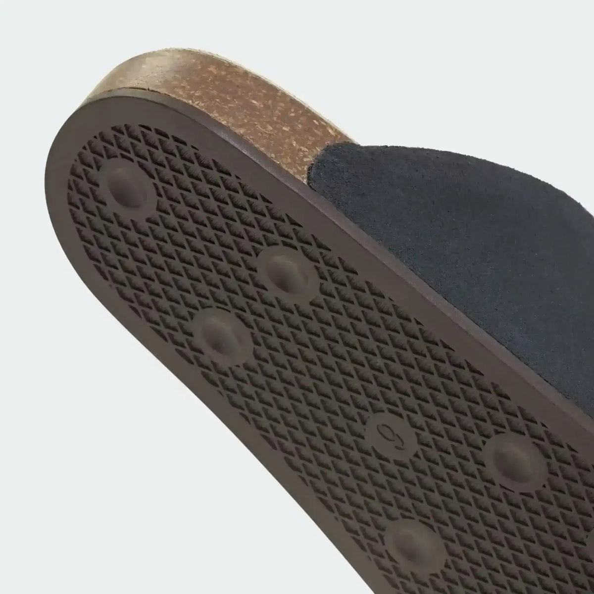 Dark slide-shoe outsole with honeycomb-like heel tread, close-up.