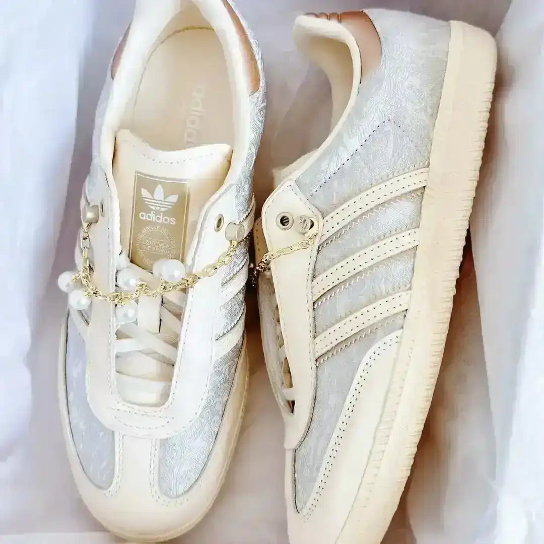 Beige Adidas leather sneakers detailed with pearls, a gold chain and textured fabric panels, offering a luxurious yet casual fashion statement.