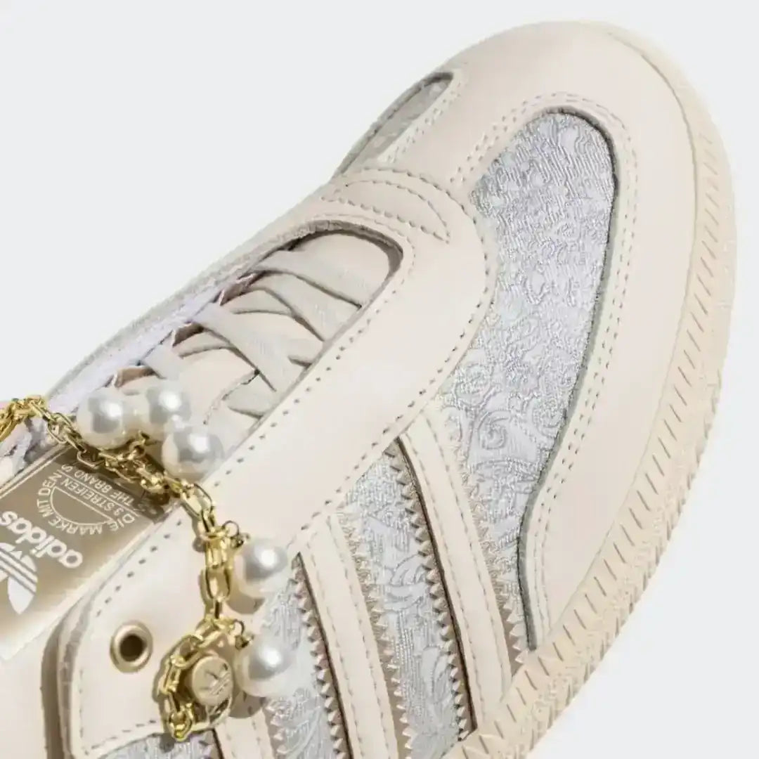 Adidas beige sneakers enhanced with pearls, gold chain elements and textured fabric panels for a fashion-forward and elegant everyday appeal.