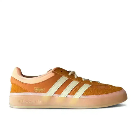 Orange and cream three-stripe low-top sneakers with gum soles.