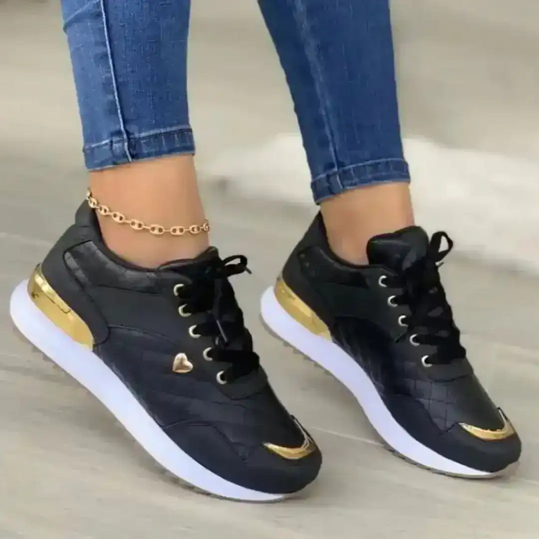 Close up of white fashion sneaker showing metallic gold heel detail, perforated upper, and white laces