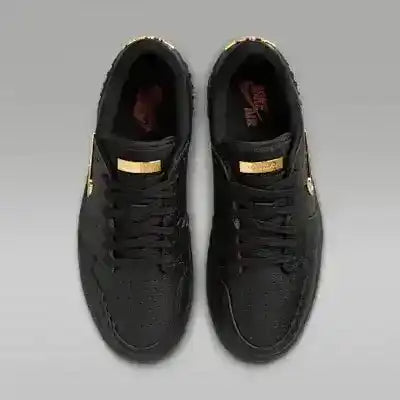 Black low-top sneakers with gold-colored swoosh details.