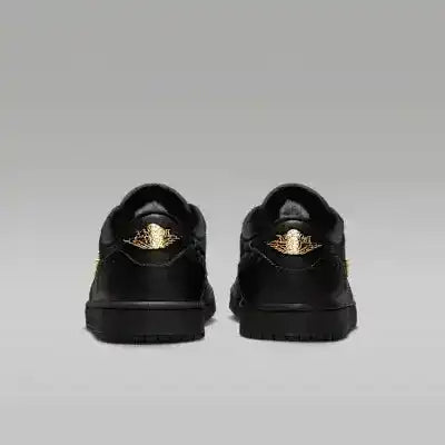 Black low-top sneakers with gold-colored swoosh details.