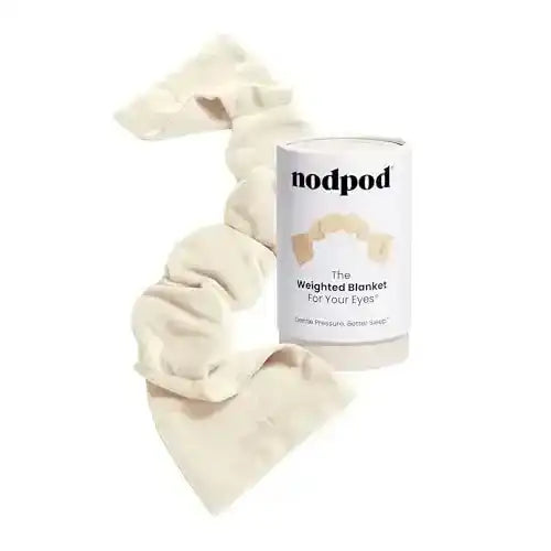 Cream fabric sleep mask beside its cylindrical package.