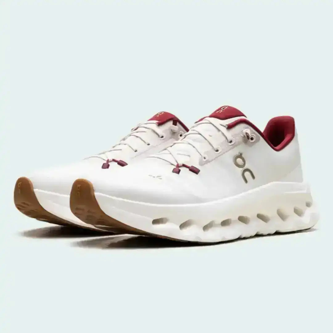 Off-white lace-up sneakers with red collar accents and cutout-style midsoles.
