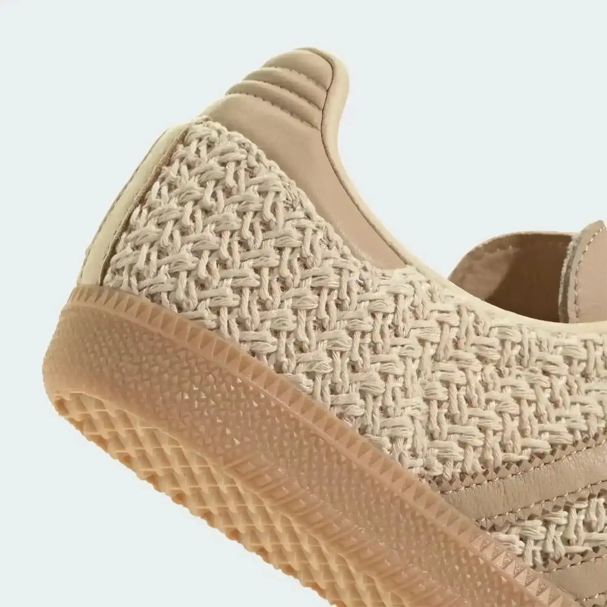 Close-up of a beige sneaker's woven heel and gum sole.