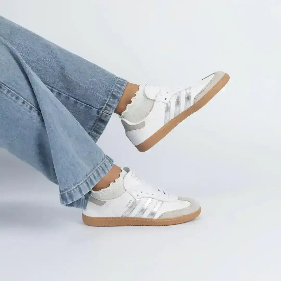 White and light gray three-stripe sneakers with gum soles.
