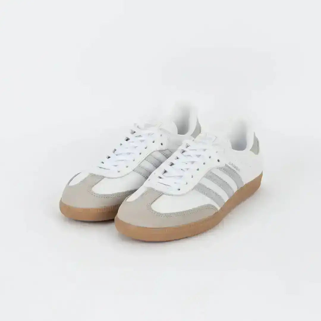 White and light gray three-stripe sneakers with gum soles.