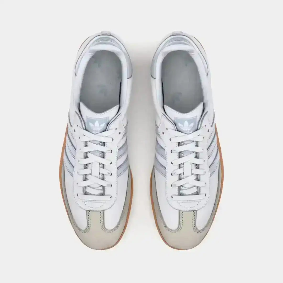 White and light gray three-stripe sneakers with gum soles.