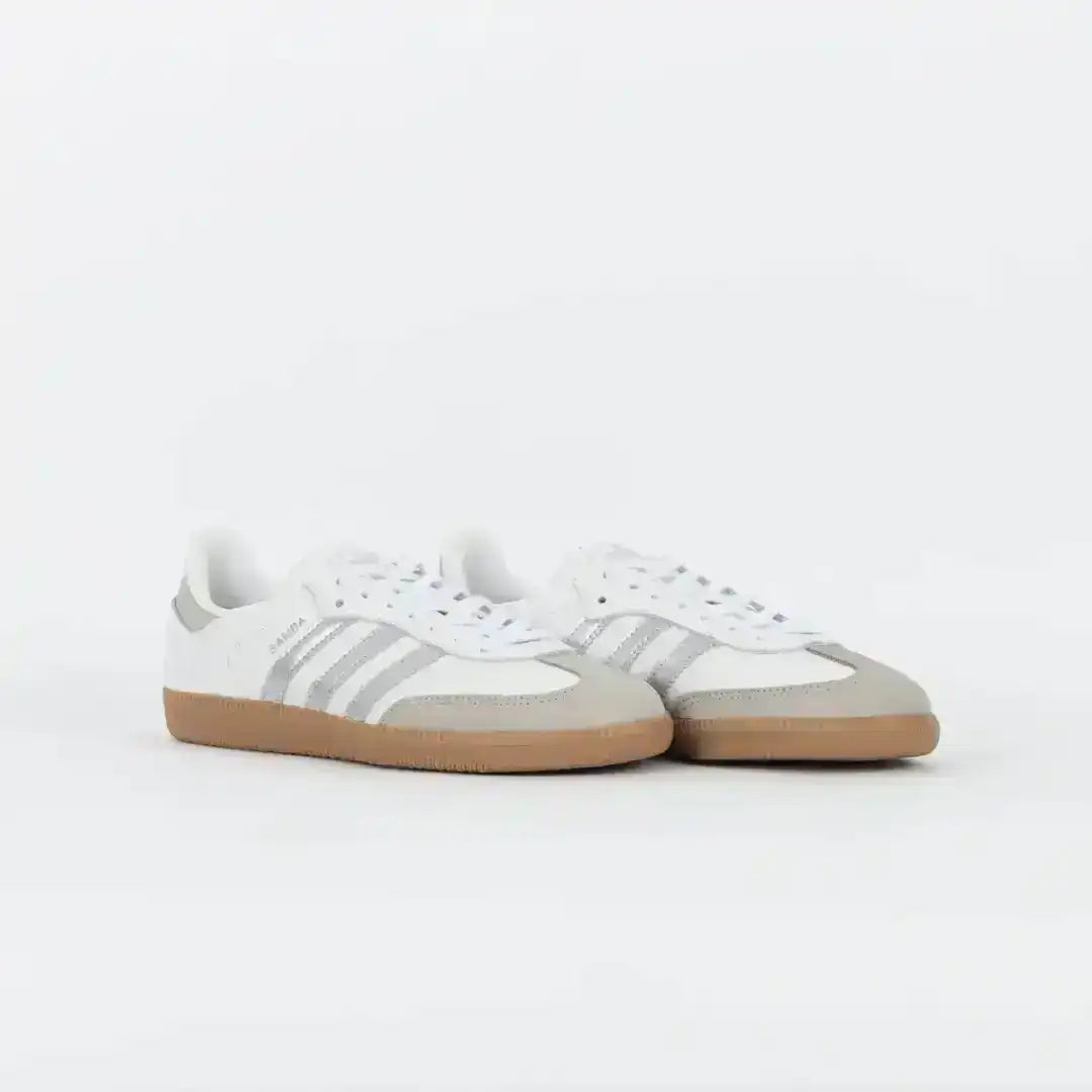 White and light gray three-stripe sneakers with gum soles.